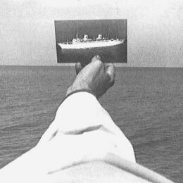 Ein Mensch hält ein Bild eines Bootes vor dem Meer